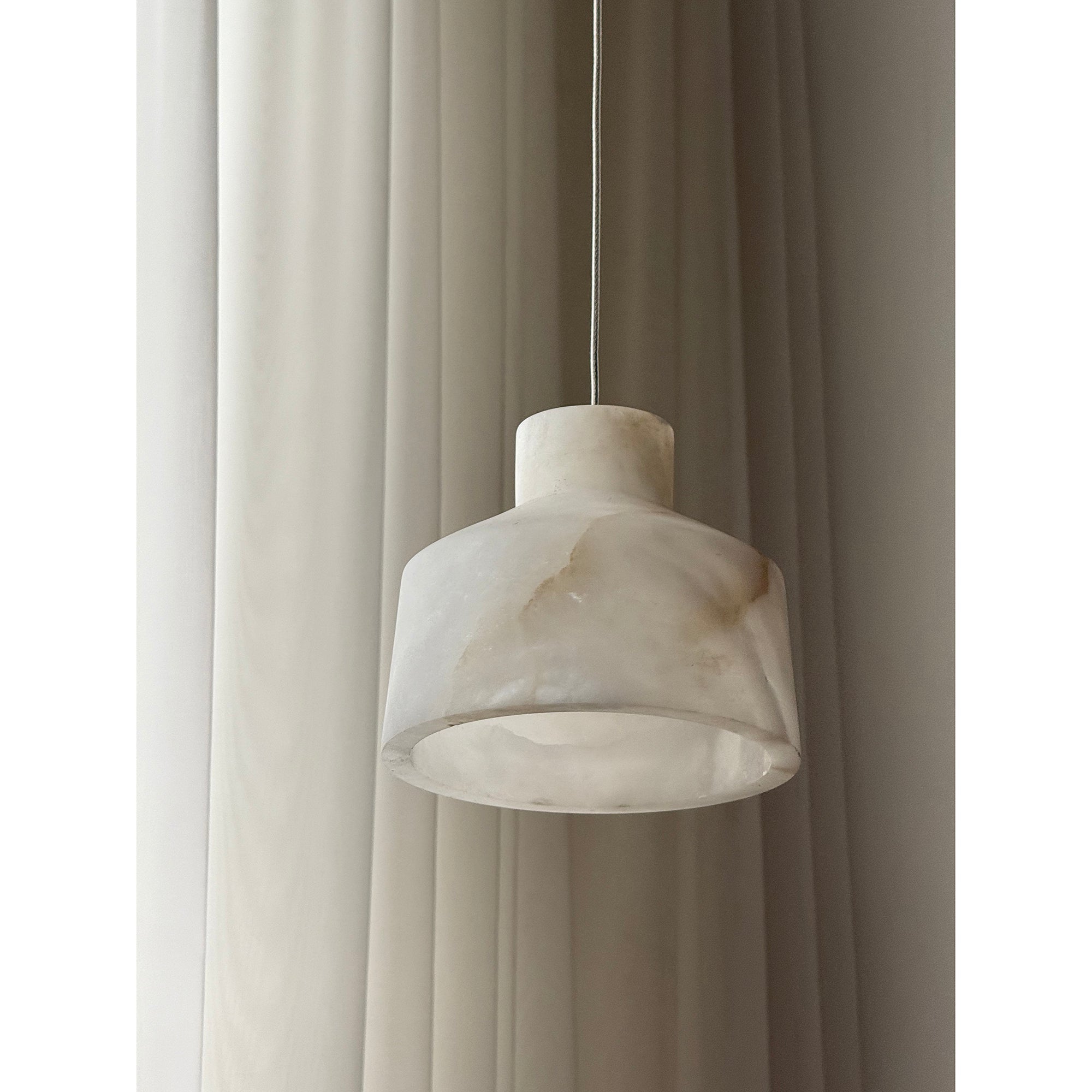 Close view of the Clérachic Alabaster Pendant Light, the stepped drum shade cut from white stone with faint amber seams.