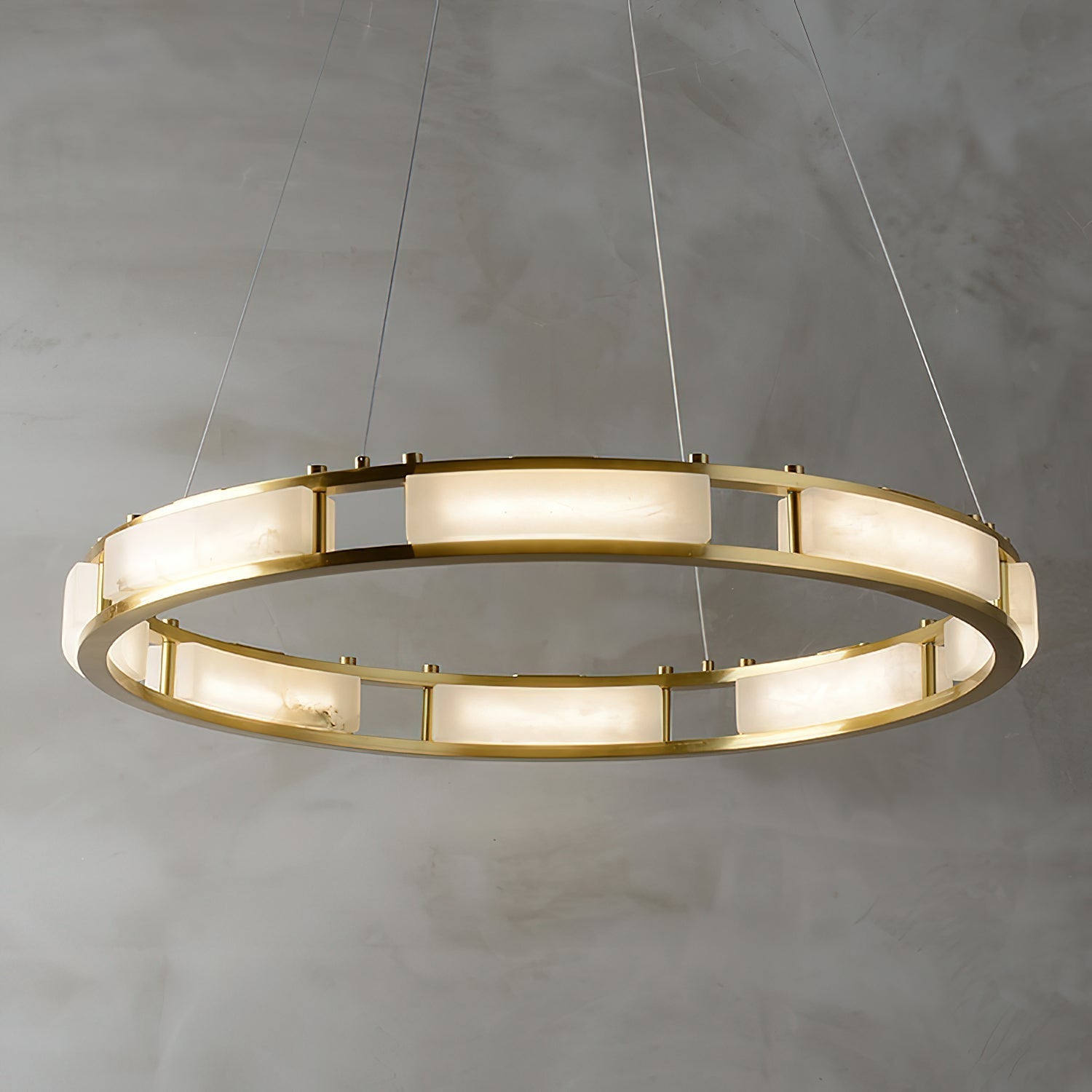 The wider Clérachic Alabaster Ring Chandelier seen from above, ten lit alabaster panels ringing the brass frame over a plaster wall.