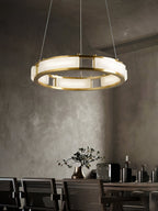 Clérachic Alabaster Ring Chandelier lighting a concrete-walled dining room above caned chairs and a long timber table.