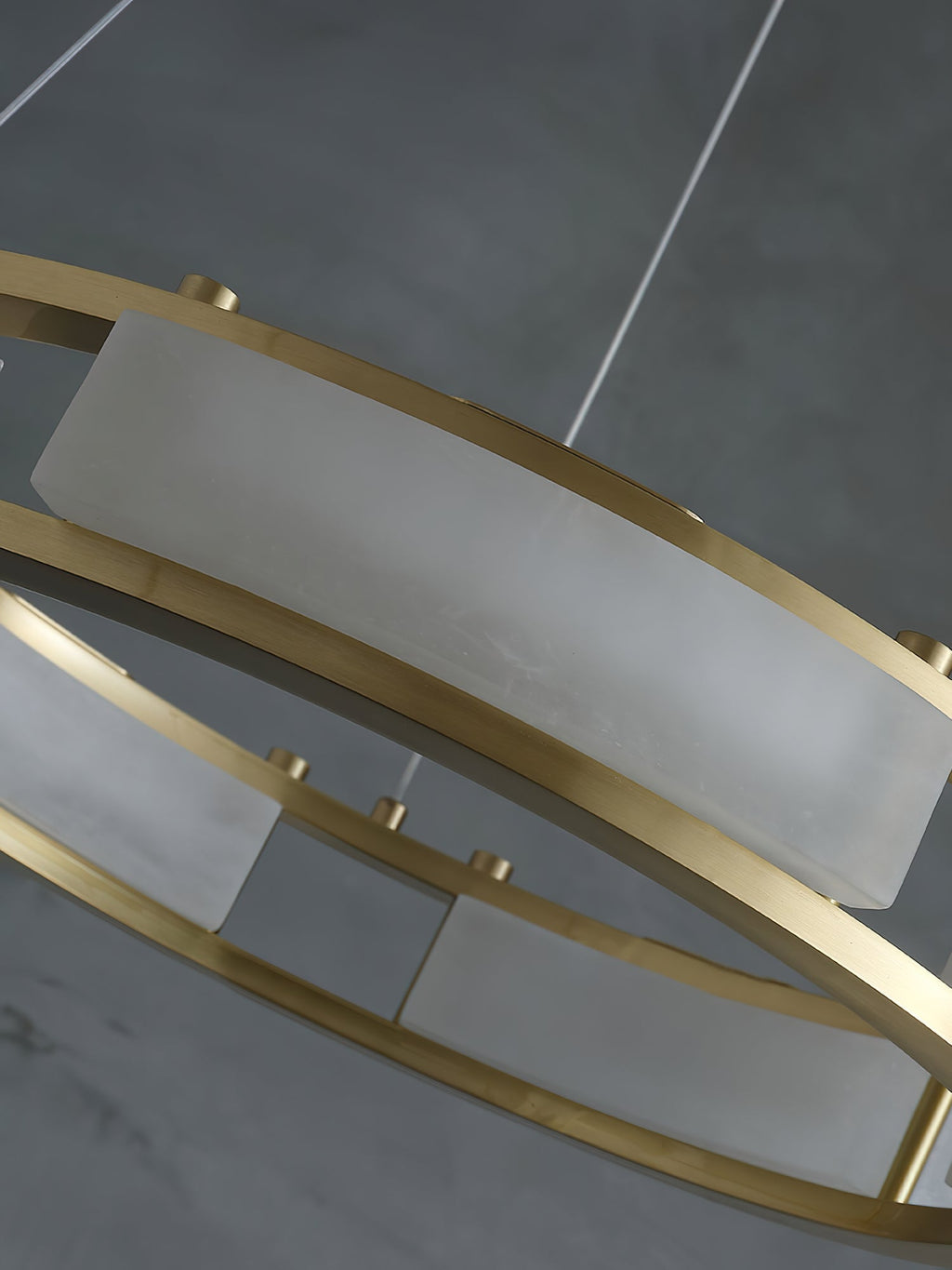 Close view of a Clérachic Alabaster Ring Chandelier panel, quarried stone curved to the ring and held by brushed brass rails.