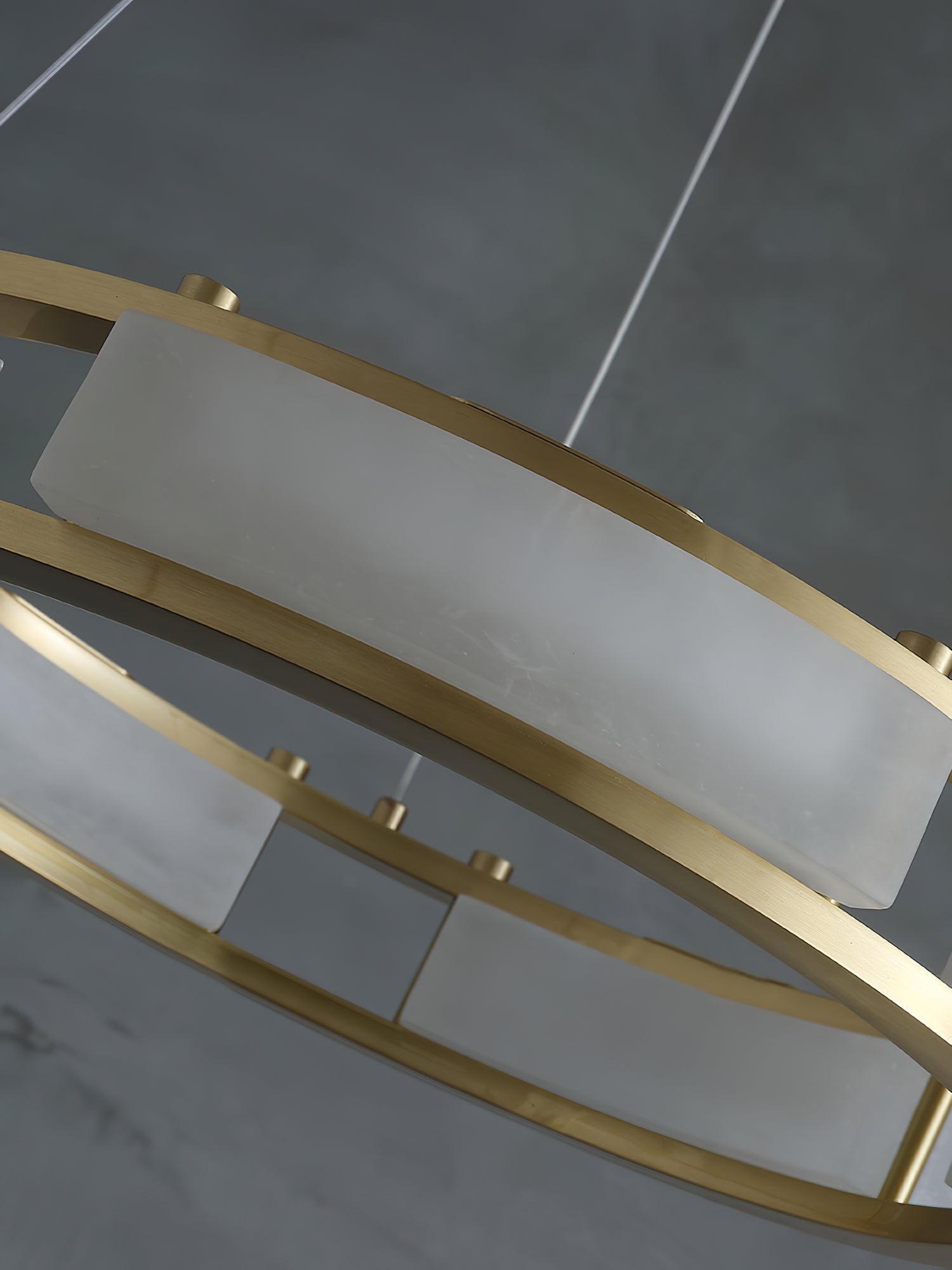 Close view of a Clérachic Alabaster Ring Chandelier panel, quarried stone curved to the ring and held by brushed brass rails.