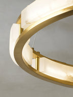 Detail of the Clérachic Alabaster Ring Chandelier lit, warm light spilling from the stone panels onto the polished brass ring.