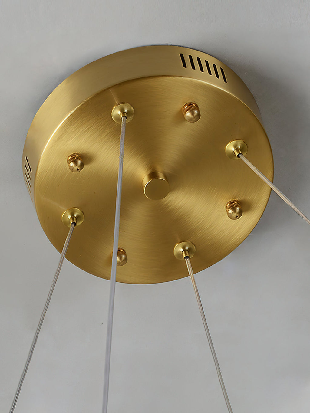 The brass ceiling canopy of the Clérachic Alabaster Ring Chandelier, vent slots and cable grips holding the clear suspensions.