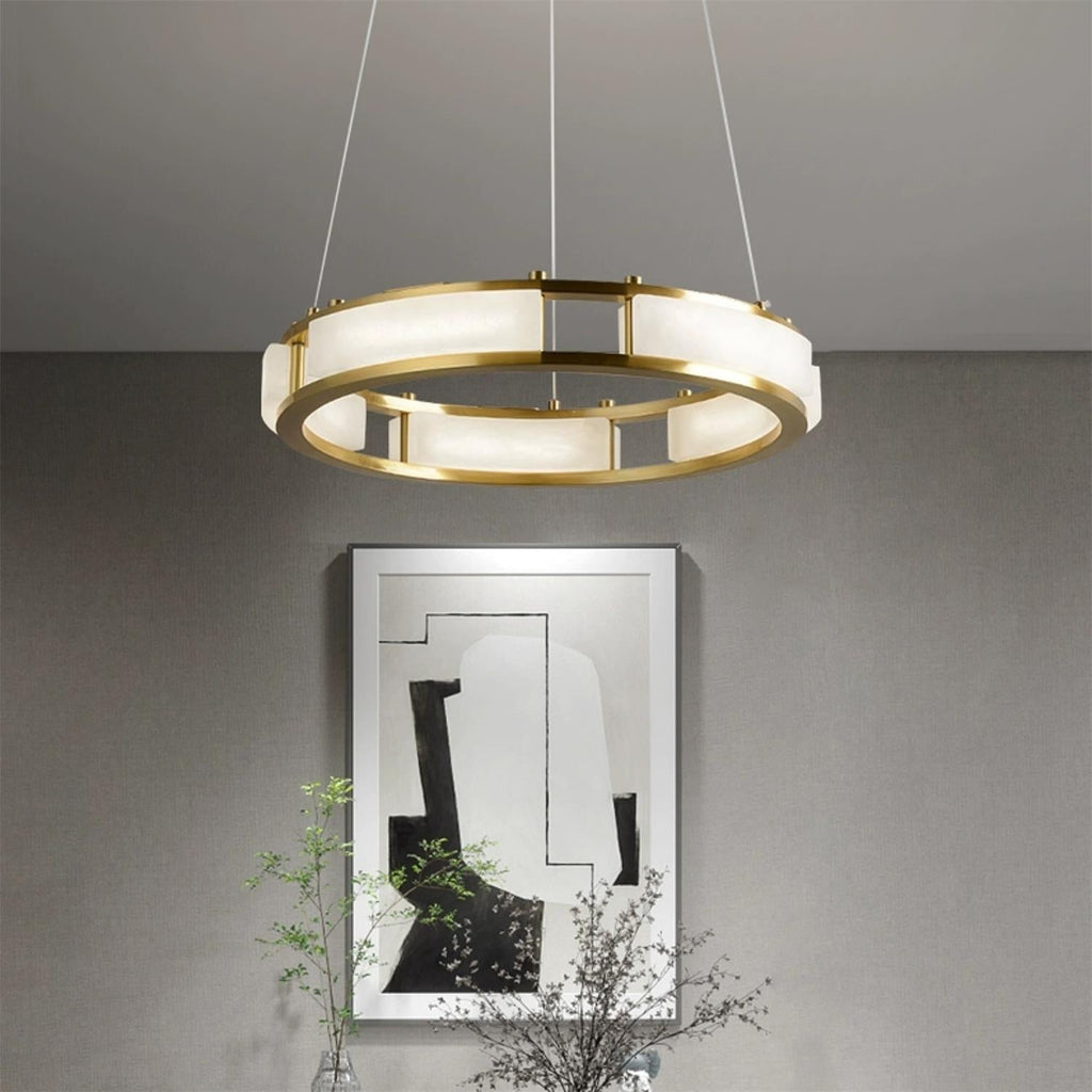 Clérachic Alabaster Ring Chandelier lit above a framed abstract print in a grey living room with branches in a glass vase.