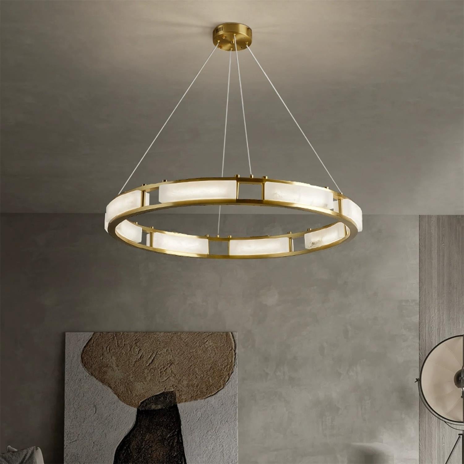 Clérachic Alabaster Ring Chandelier hung from its canopy in a concrete-walled room above a textured stone artwork.
