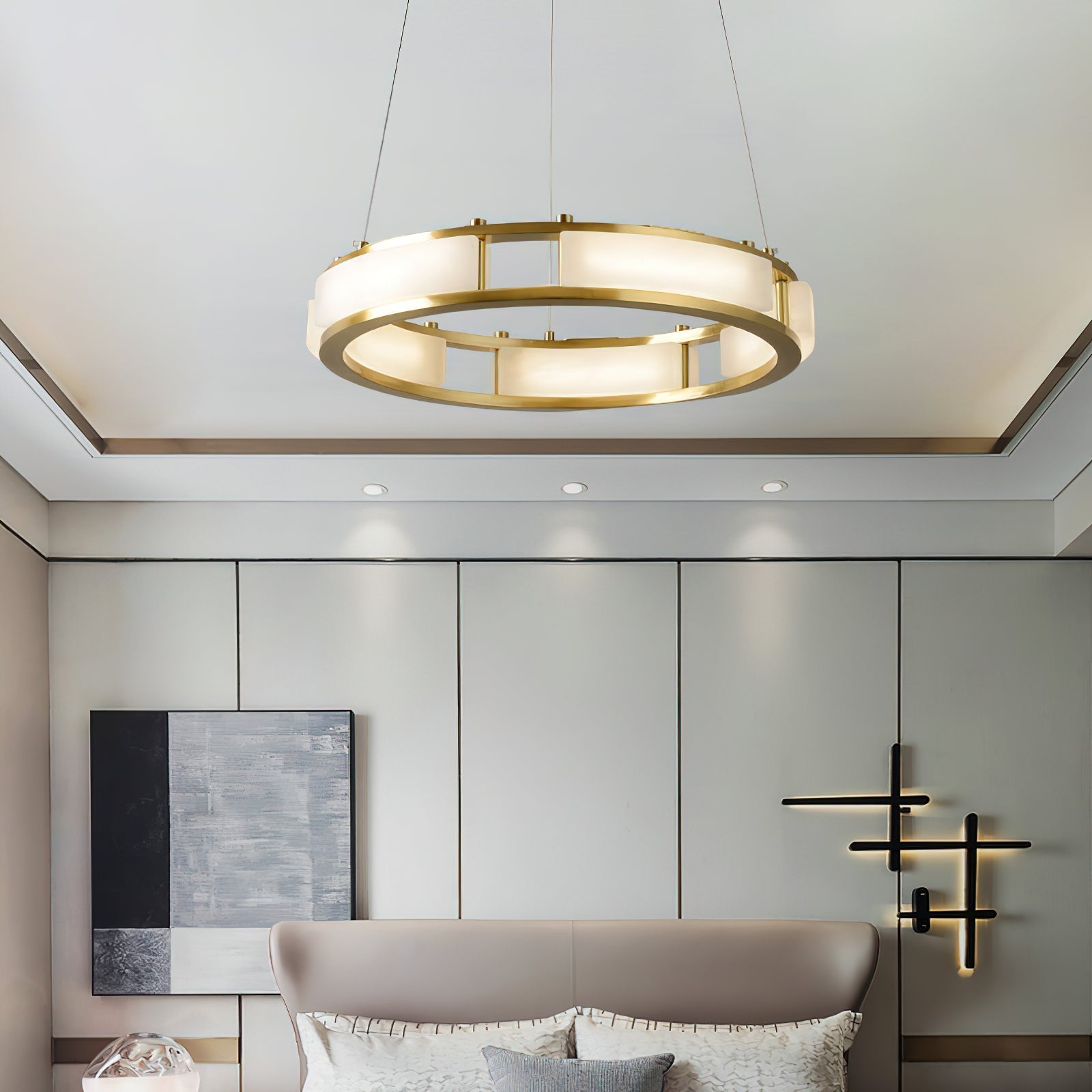 Clérachic Alabaster Ring Chandelier glowing over a bed in a panelled bedroom, recessed downlights washing the wall behind.