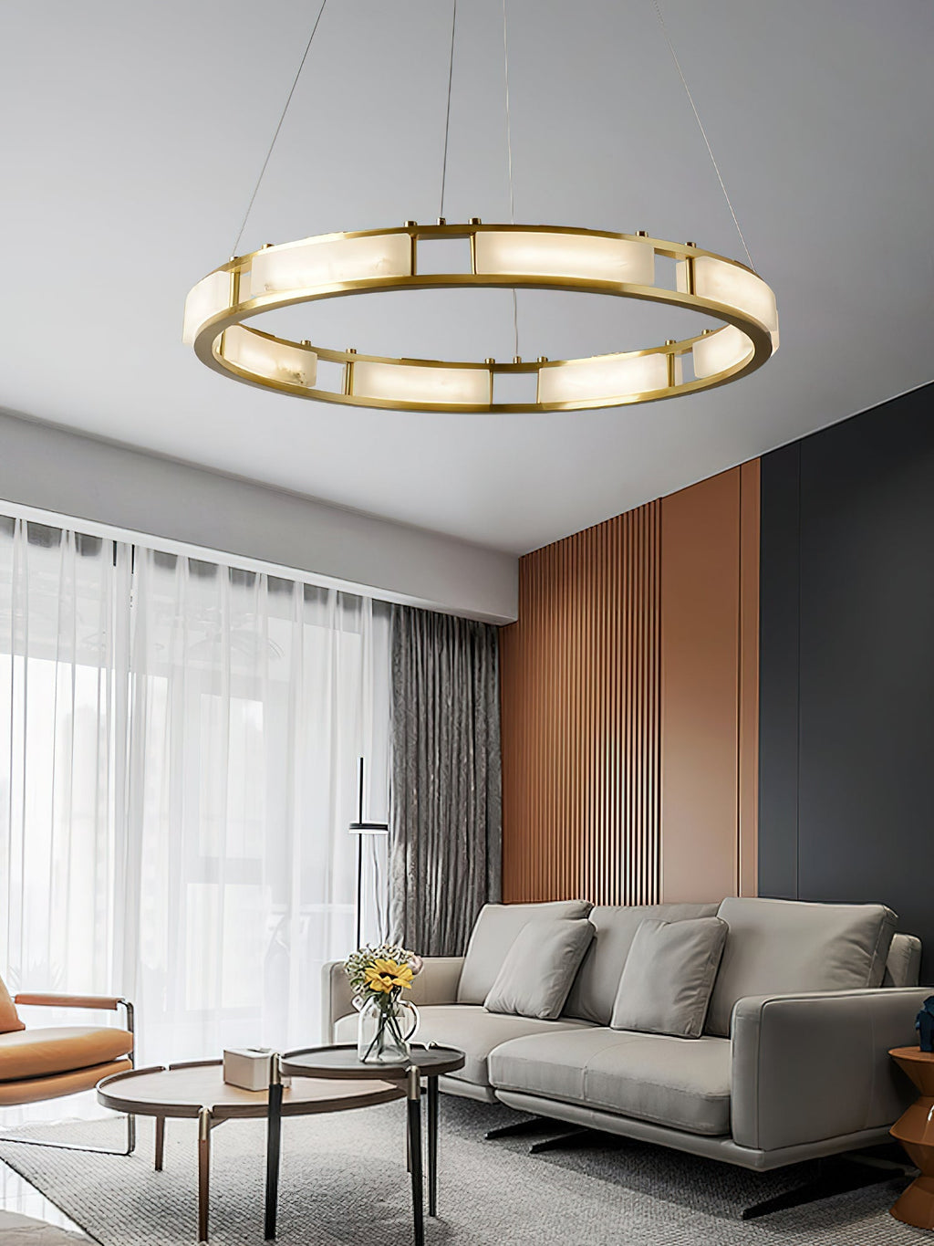 Clérachic Alabaster Ring Chandelier lighting a living room above a grey sofa, sheer curtains and a fluted terracotta wall.