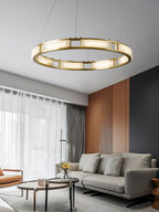 Clérachic Alabaster Ring Chandelier lighting a living room above a grey sofa, sheer curtains and a fluted terracotta wall.