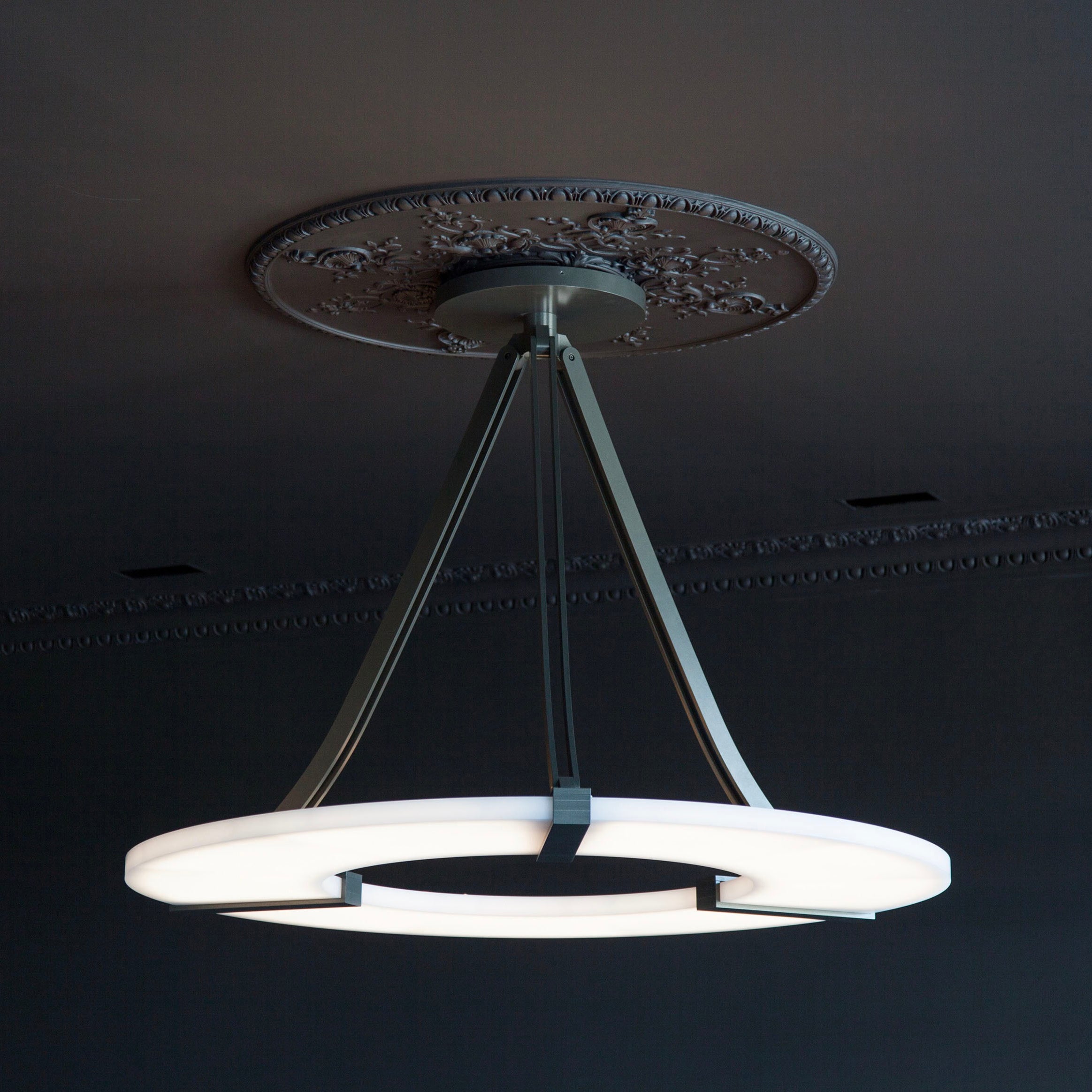 Clérachic Alabaster Ring Chandelier fitted to an ornate ceiling rose in a dark panelled room, the ring glowing softly below it.