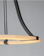 Close detail of the Clérachic Alabaster Ring Chandelier where a bronze strap clamps the glowing stone band to its curved arm.