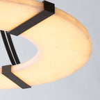 Clérachic Alabaster Ring Chandelier close up from beneath, warm light pooling through the veined stone between two bronze straps.