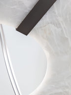 Clérachic Alabaster Ring Chandelier detail, a dark bronze strap laid over the crystalline white stone at the ring's inner curve.