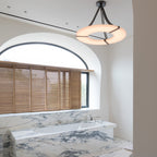 Clérachic Alabaster Ring Chandelier glowing above a marble-clad room with an arched window and louvred timber shutters.