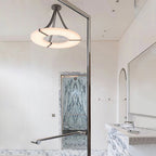 Clérachic Alabaster Ring Chandelier in a pale marble-lined room, its warm ring set against a tall polished glass screen.