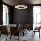 Clérachic Alabaster Ring Chandelier lighting a dark panelled lounge of leather chairs and a low table by the terrace doors.