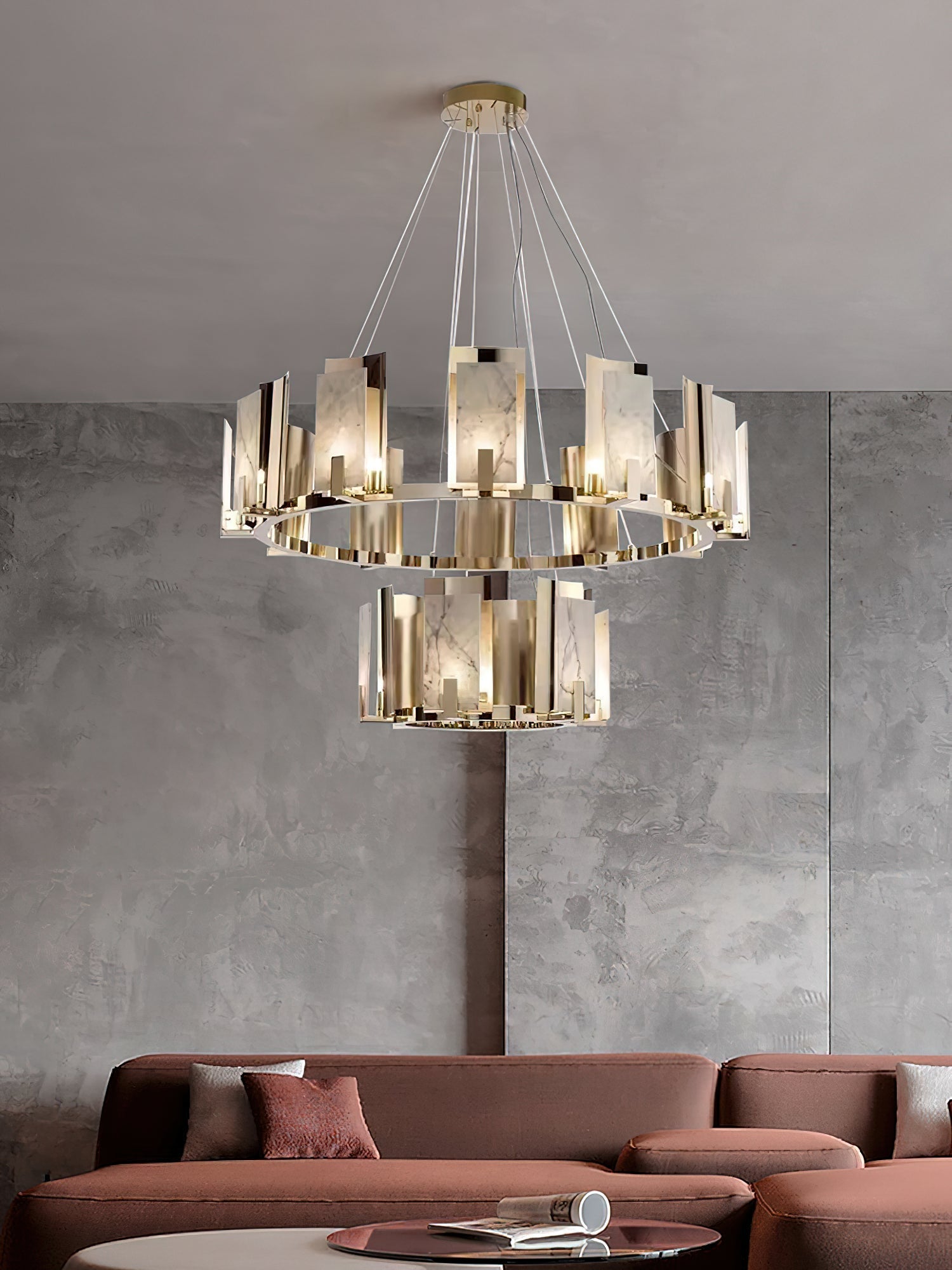 Two-tier Clérachic Alabaster Ring Chandelier above a terracotta sofa, filling the height of a polished concrete wall.