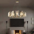 Clérachic Alabaster Ring Chandelier lit in a dim living room above a wall-mounted screen and the glow of a lit fireplace.