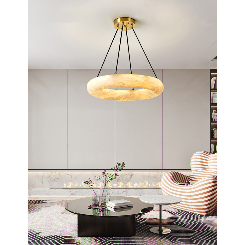 Clérachic Alabaster Ring Chandelier lit over a black round table in a lounge with a striped armchair and a long fireplace.