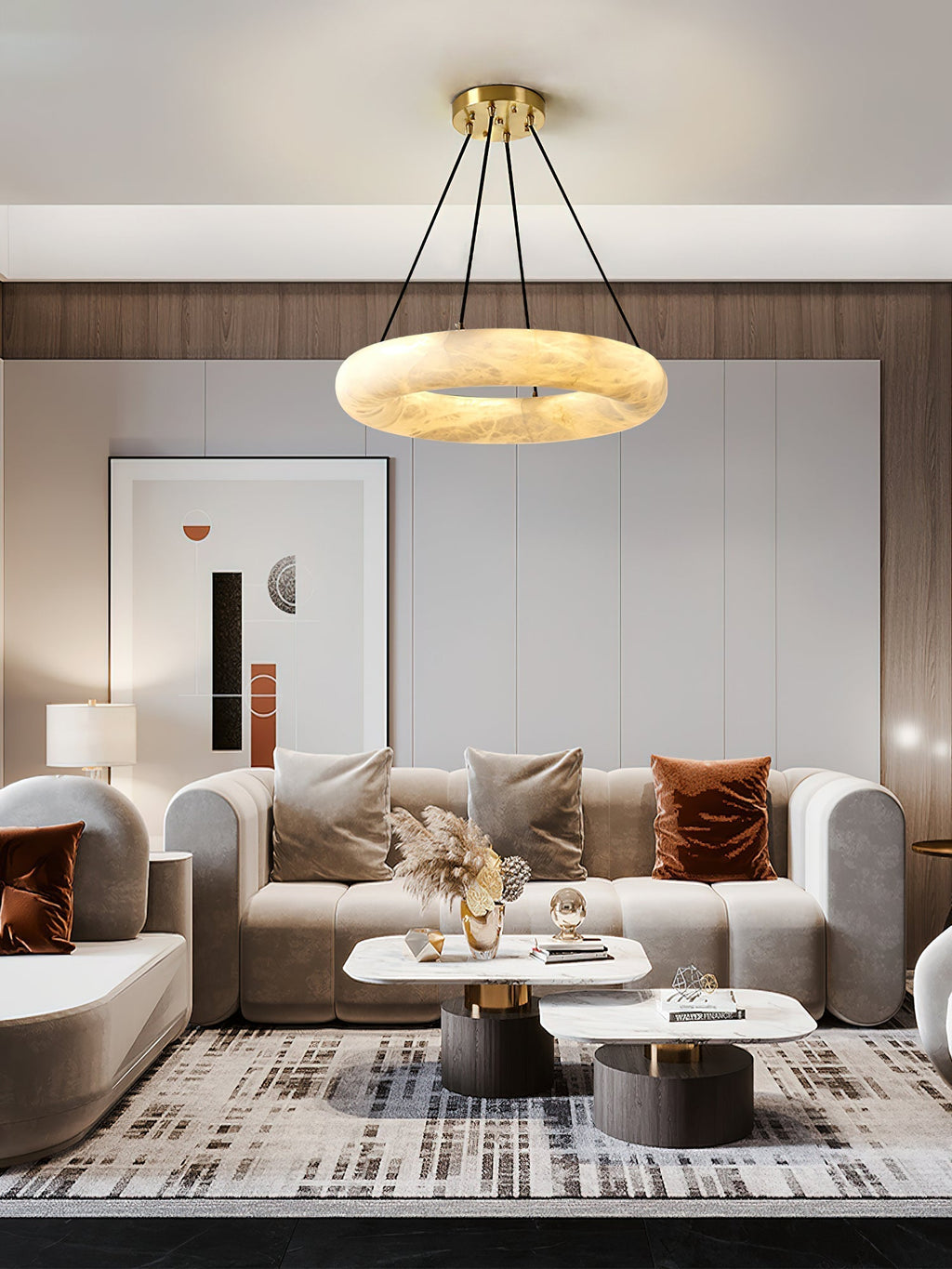 Clérachic Alabaster Ring Chandelier warm-lit above a beige sofa, framed print and pampas grass in a panelled living room.