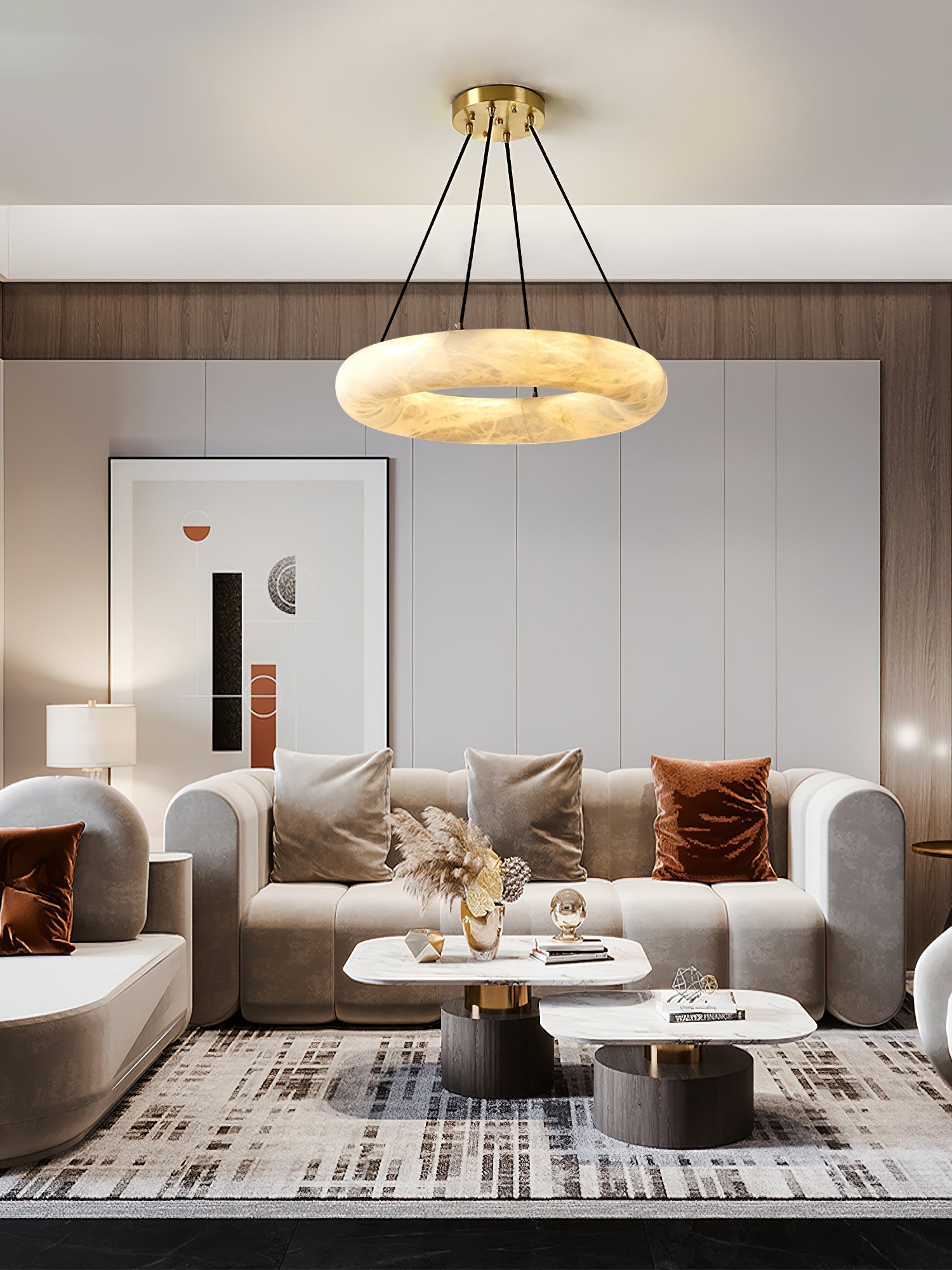 Clérachic Alabaster Ring Chandelier warm-lit above a beige sofa, framed print and pampas grass in a panelled living room.
