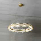 The warm-lit ring of the Clérachic Alabaster Ring Chandelier, alabaster diamonds alternating with pierced brass fins.