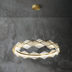 Clérachic Alabaster Ring Chandelier glowing against a dark concrete wall, the brass fins raking the light into fine lines.