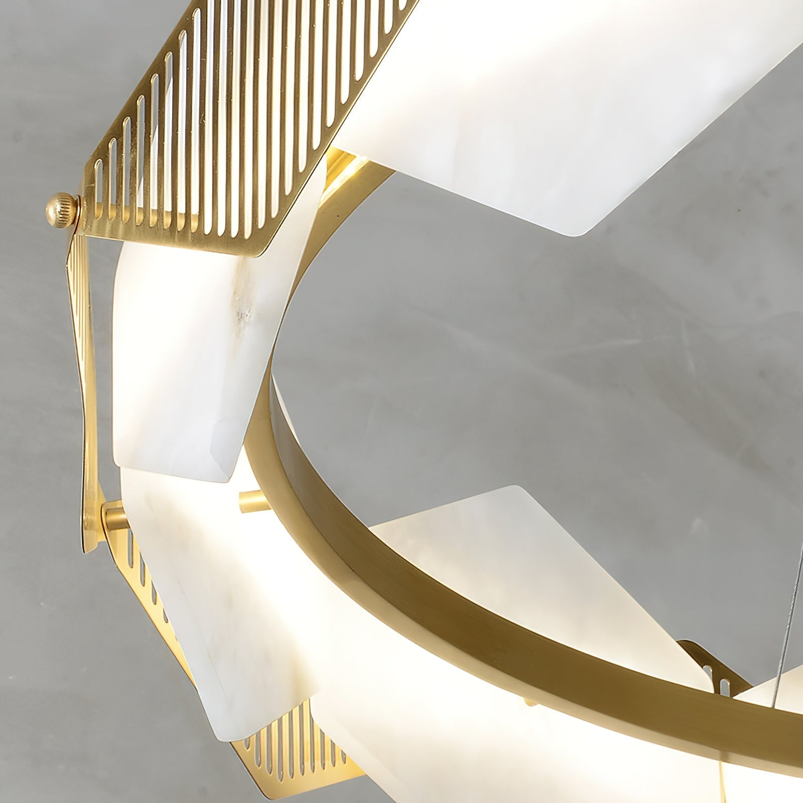 Close-up of the Clérachic Alabaster Ring Chandelier, a slotted brass fin meeting the veined alabaster panels on the ring.