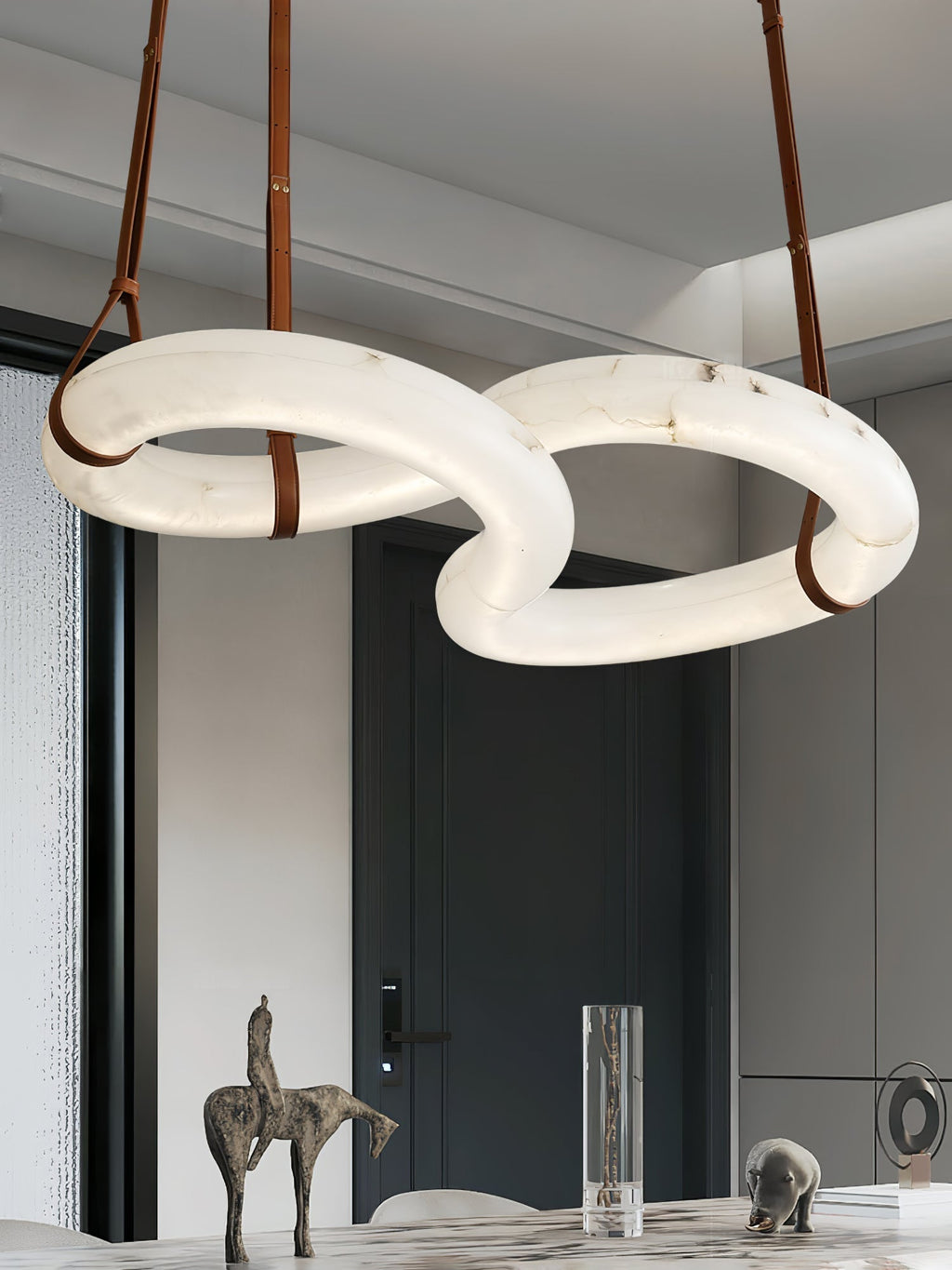 Clérachic Alabaster Ring Chandelier over a marble dining table, three tan leather straps running up to the white ceiling.