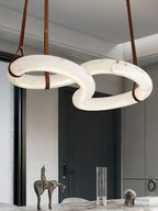 Clérachic Alabaster Ring Chandelier over a marble dining table, three tan leather straps running up to the white ceiling.