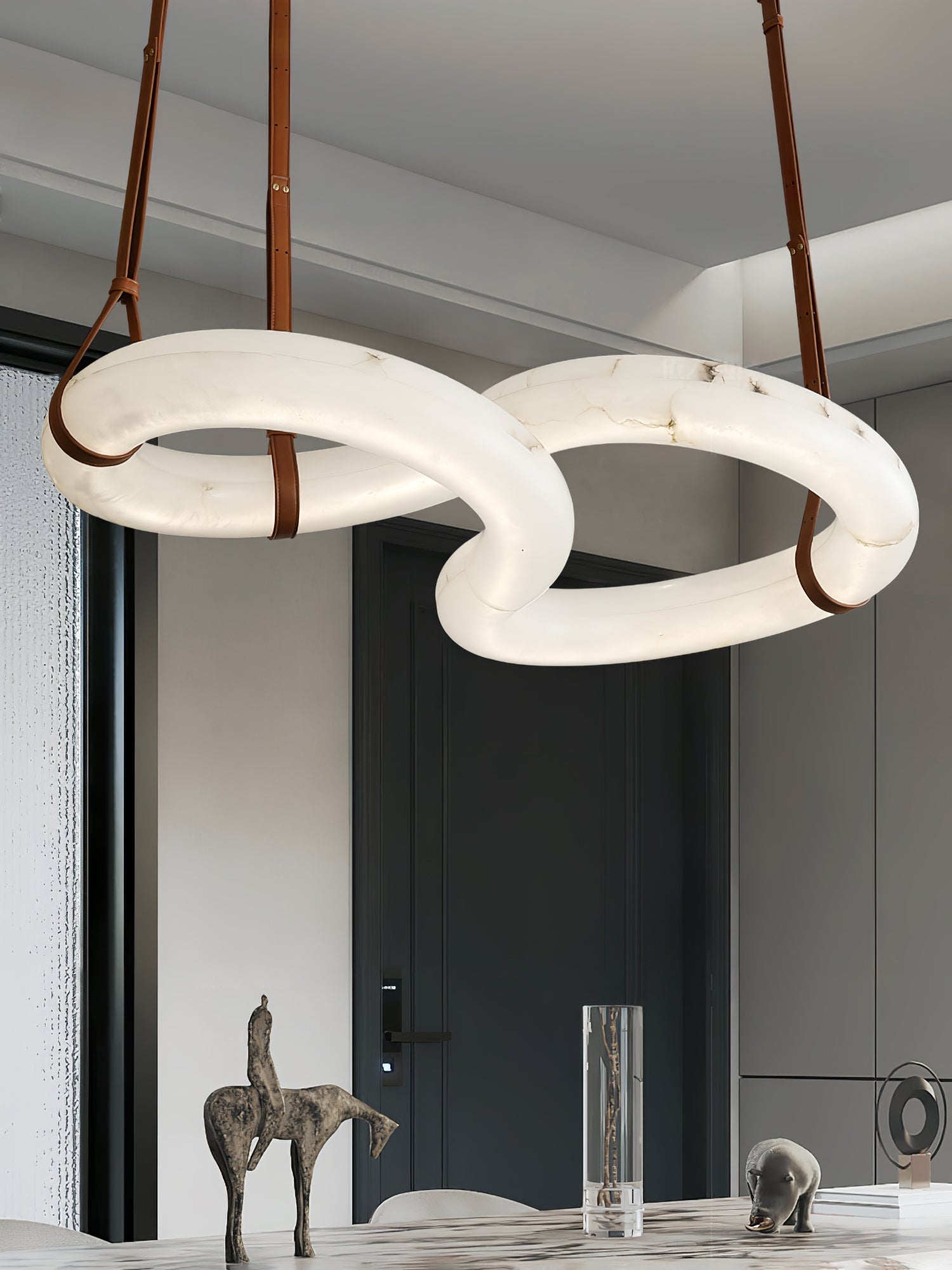 Clérachic Alabaster Ring Chandelier over a marble dining table, three tan leather straps running up to the white ceiling.