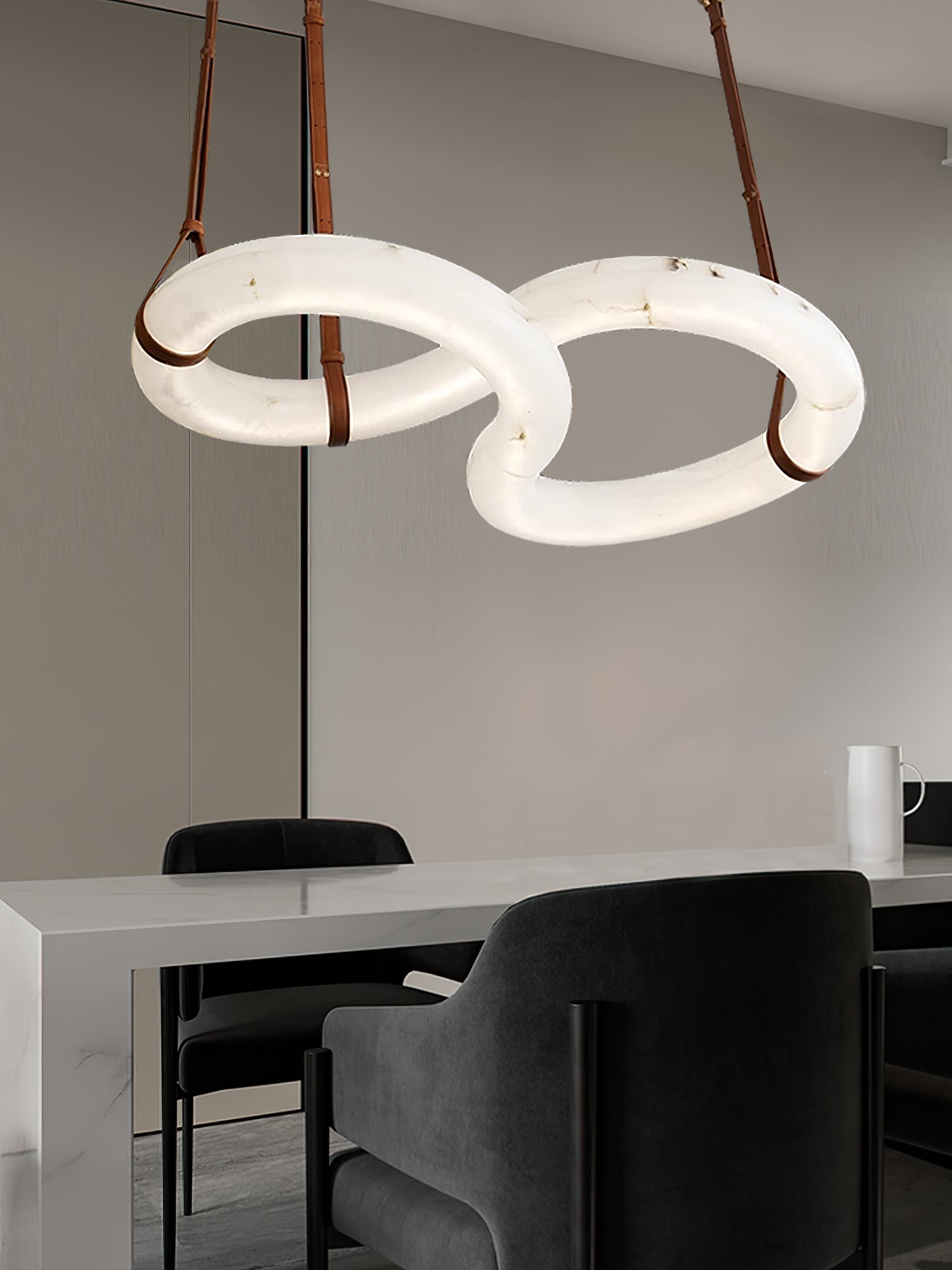 Lit Clérachic Alabaster Ring Chandelier above a white marble dining table, mirrored wall and dark velvet chairs behind it.