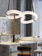 Clérachic Alabaster Ring Chandelier glowing over a marble kitchen island, sheer curtains and bar stools in the background.