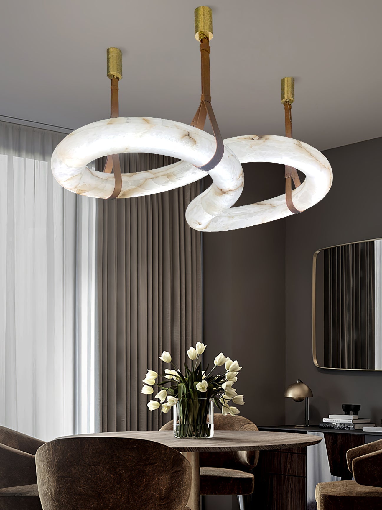 Clérachic Alabaster Ring Chandelier lighting a round dining table with white tulips, brass canopies fixed to the ceiling.