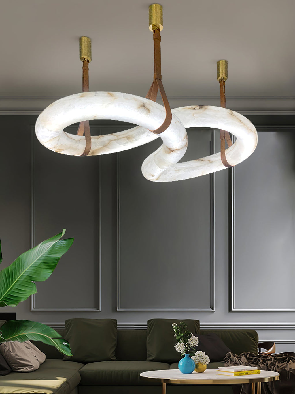 Clérachic Alabaster Ring Chandelier hung over a living room with an olive sofa and panelled grey walls, rings lit from within.