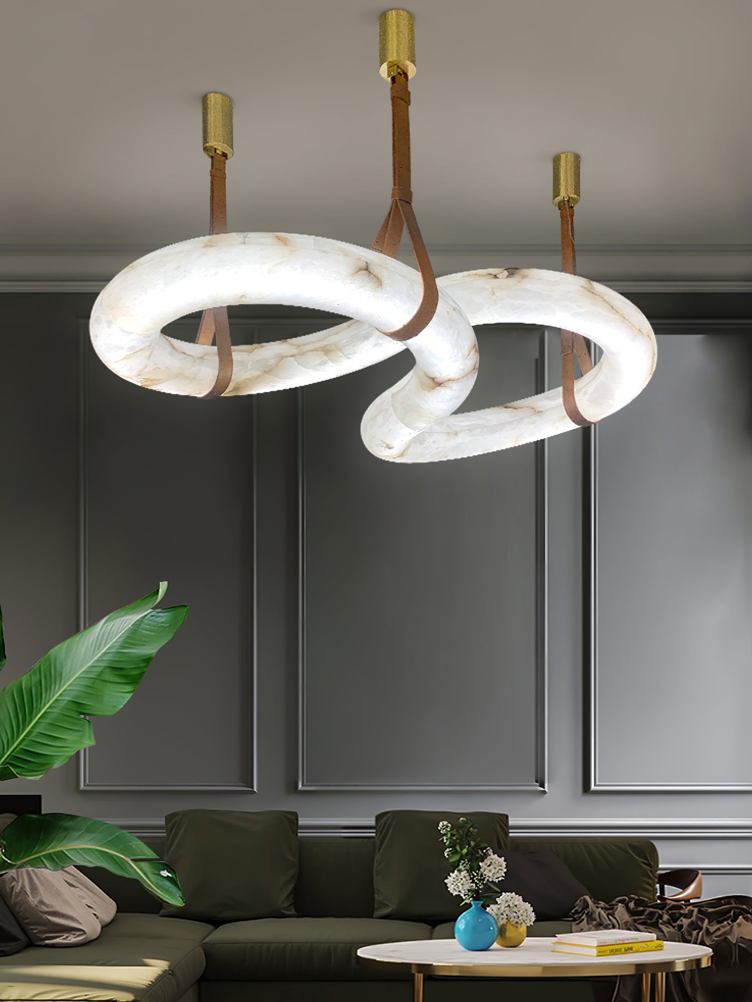Clérachic Alabaster Ring Chandelier hung over a living room with an olive sofa and panelled grey walls, rings lit from within.