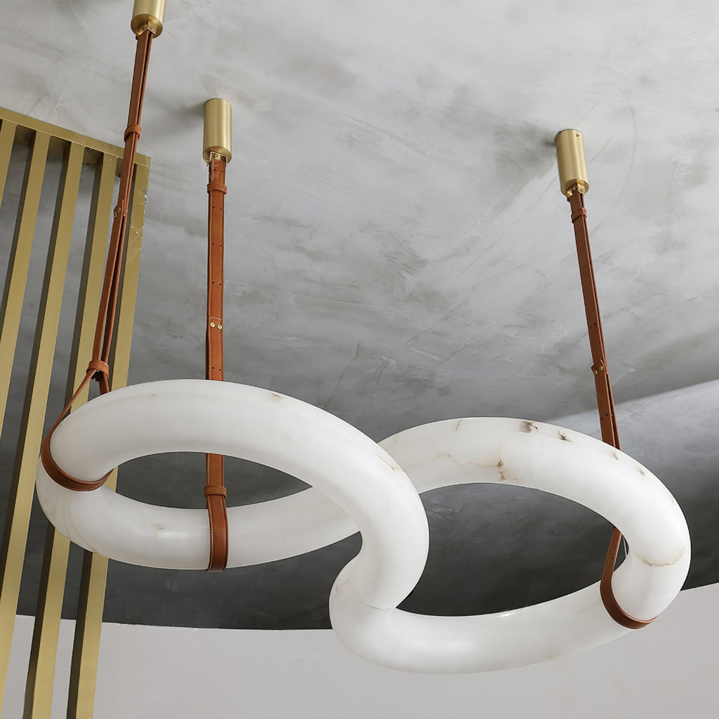 Clérachic Alabaster Ring Chandelier seen from below in a concrete-ceilinged loft, brass canopies and long tan straps in view.