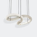 The Clérachic alabaster ring chandelier shown as two stone loops threaded through each other, hung on fine black cords.