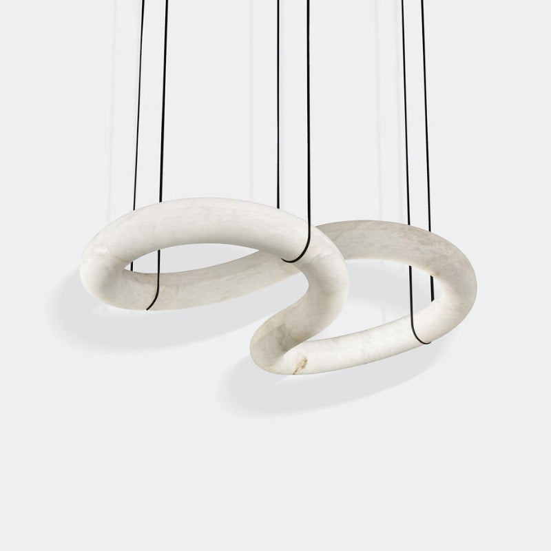 The Clérachic alabaster ring chandelier shown as two stone loops threaded through each other, hung on fine black cords.