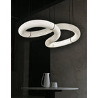 Two loops of the Clérachic alabaster ring chandelier glowing from within in a dark, stone-walled dining corner.