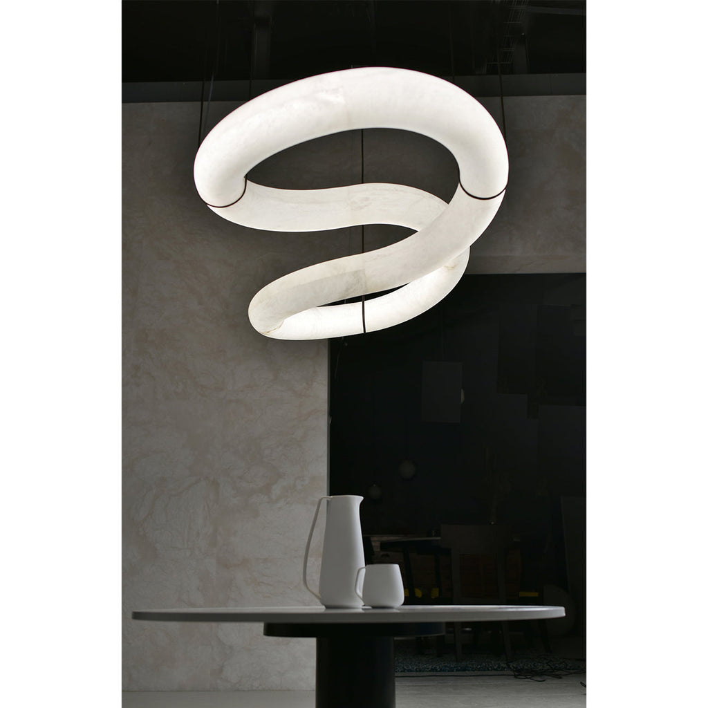 Close view from below of the Clérachic alabaster ring chandelier lit, the LED showing the veining inside each loop.