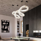 The Clérachic alabaster ring chandelier hung unlit beneath a board-formed concrete ceiling in a fireside living room.