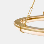 Detail of the Clérachic Alabaster Ring Chandelier, a brass chain link meeting the hoop above the warm-lit alabaster band.