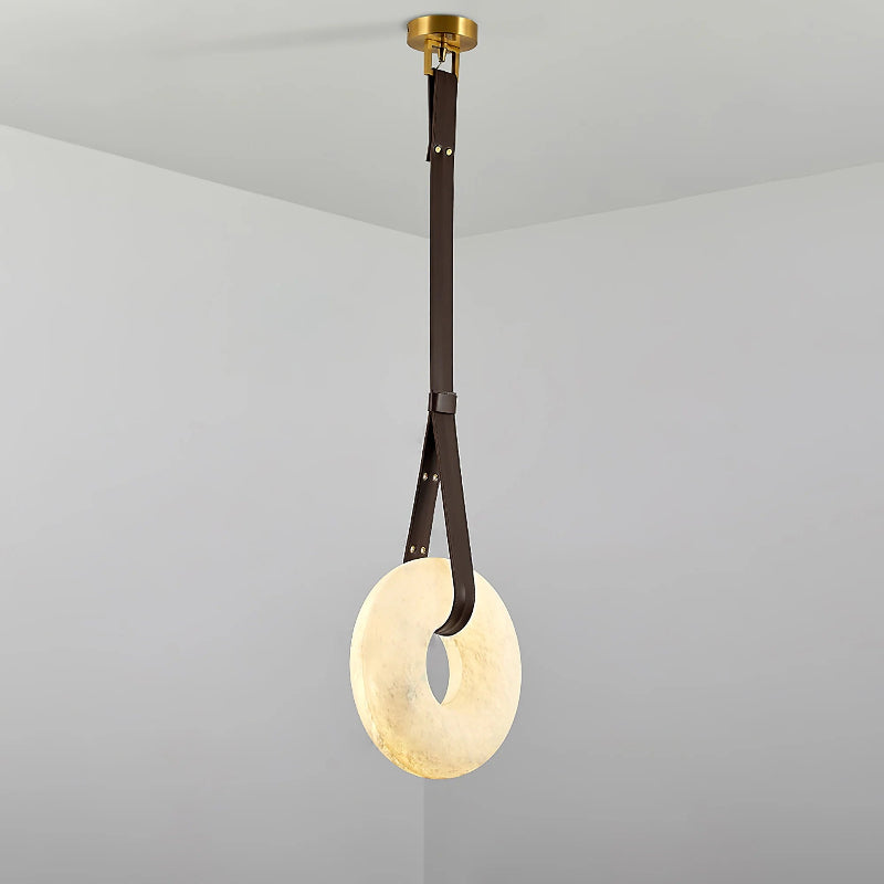Clérachic Alabaster Ring Pendant Light in the dark brown strap finish, the lit stone ring hanging in a plain grey corner.