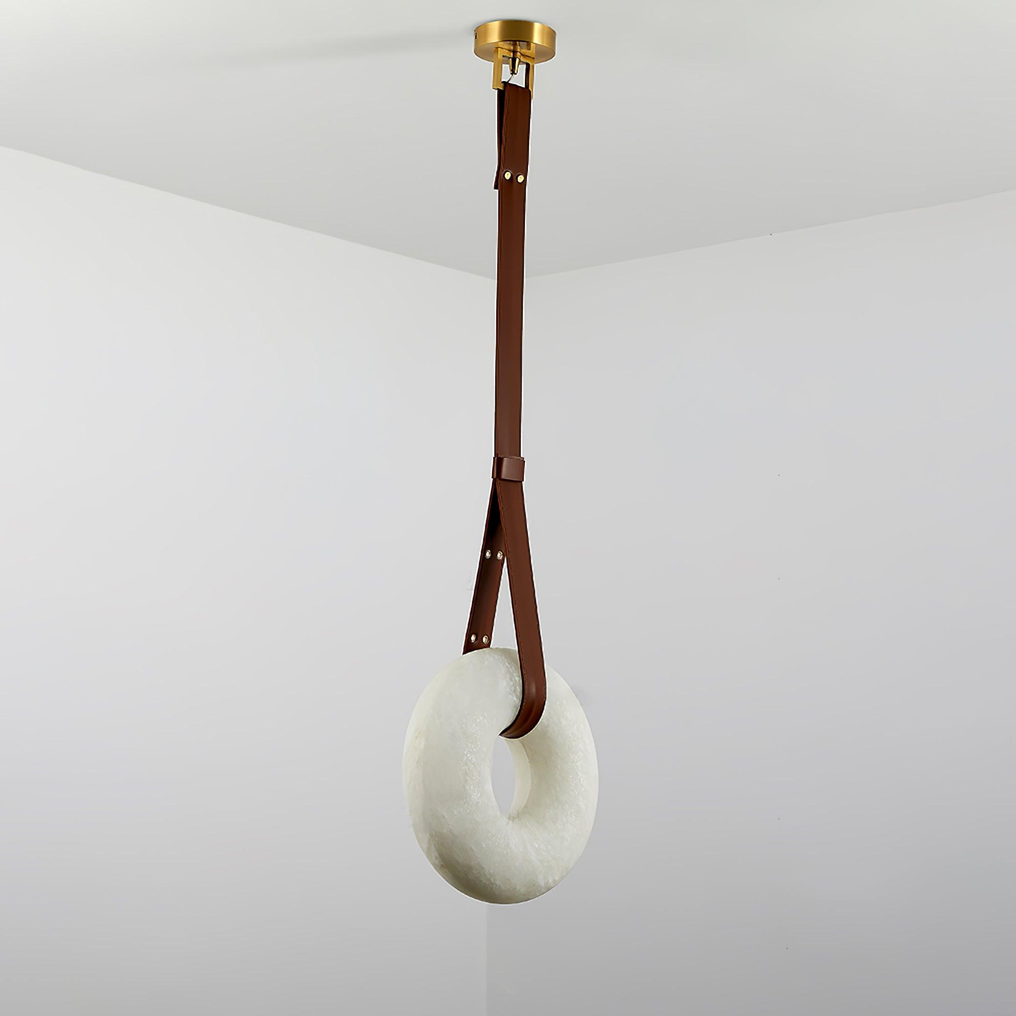 Clérachic Alabaster Ring Pendant Light hung high in a white room corner, the brown strap doubling into a loop through the ring.