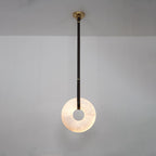 A single dark strap drops the Clérachic Alabaster Ring Pendant Light down a grey wall, the ring lit from within.