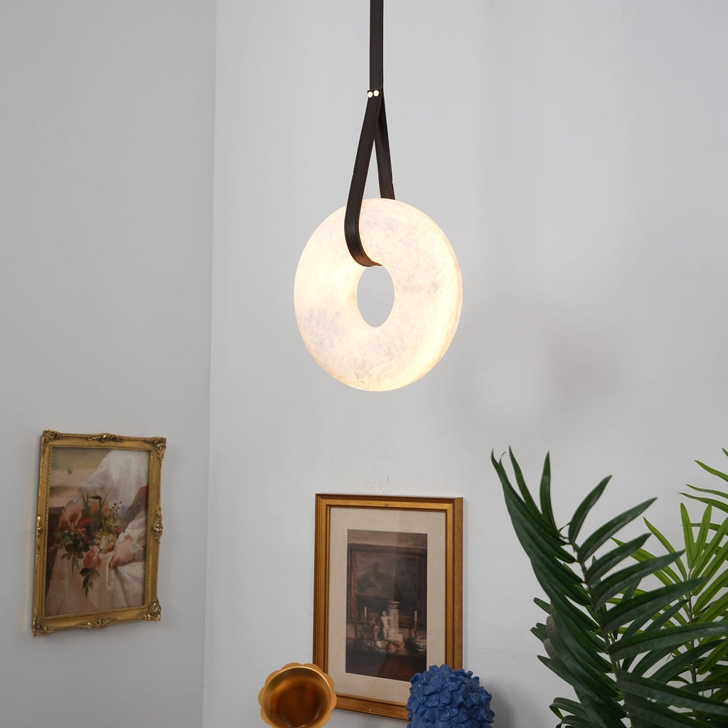 Clérachic Alabaster Ring Pendant Light lighting a corner above gilt-framed pictures, a brass gramophone horn and a palm.