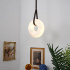 Clérachic Alabaster Ring Pendant Light lighting a corner above gilt-framed pictures, a brass gramophone horn and a palm.