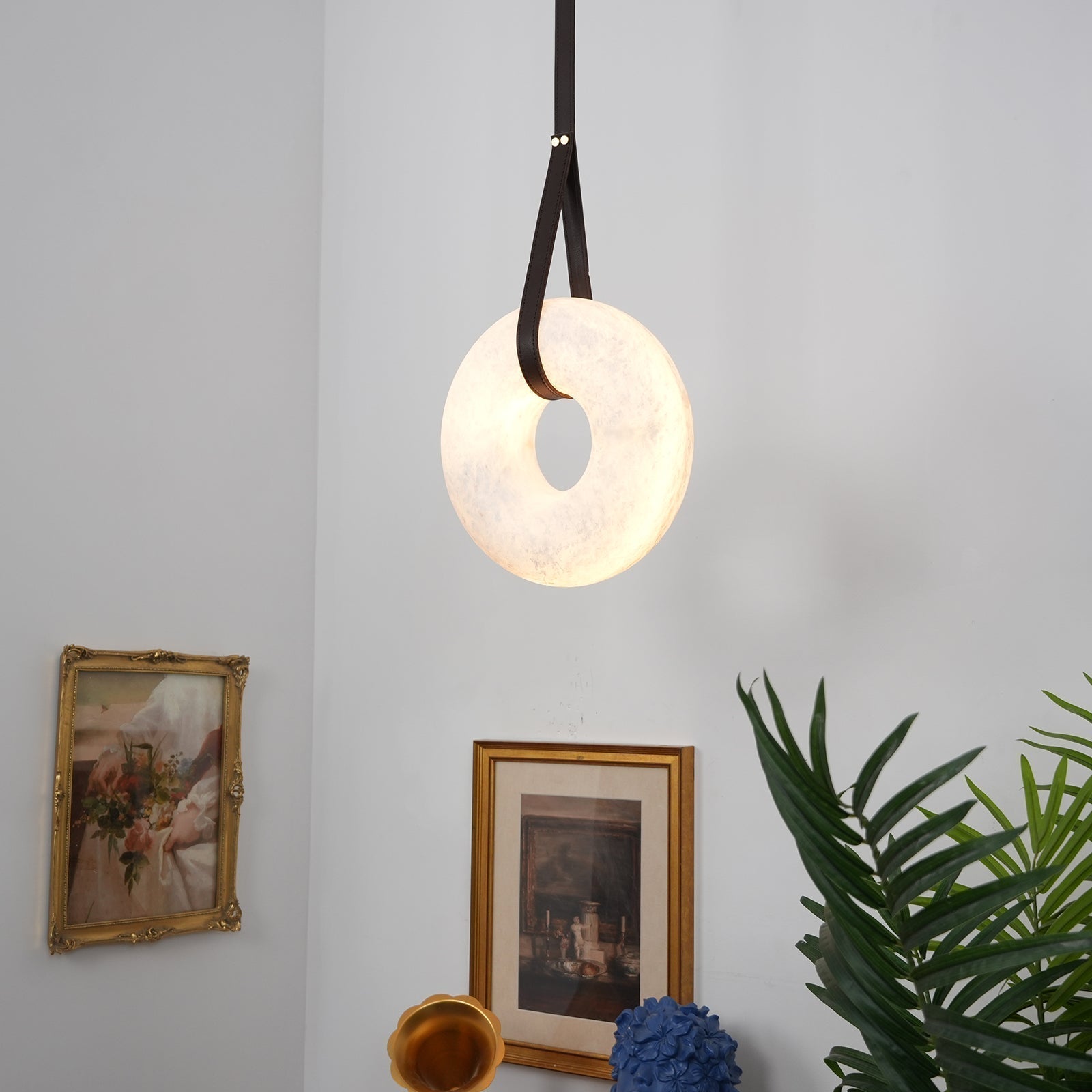 Clérachic Alabaster Ring Pendant Light lighting a corner above gilt-framed pictures, a brass gramophone horn and a palm.
