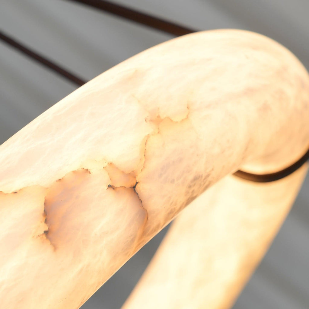 The Clérachic Alabaster Ring Pendant Light seen up close, warm light passing through the alabaster to reveal its cloudy veining.