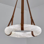 Clérachic Alabaster Ring Pendant Light seen from below on brown leather straps, the flat stone hoop filling the corner of the room.